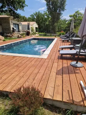 a wooden deck with a pool and a swimming pool with chairs at casasantellix in Prunelli-di-Fiumorbo