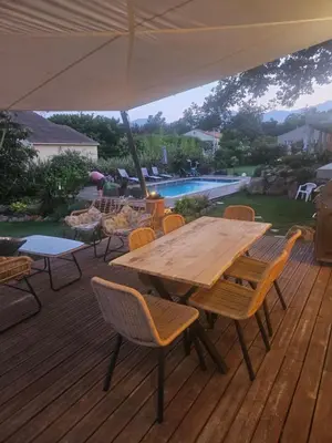 a wooden table and chairs on a deck with an umbrella at casasantellix in Prunelli-di-Fiumorbo