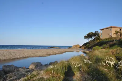 a beach with a house and the ocean at Studio en bord de mer sur Costa Serena N54 in Linguizzetta