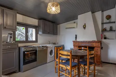 a kitchen with a table and chairs and a stove at Casa Calma - Maison à proximité des plages in Figari