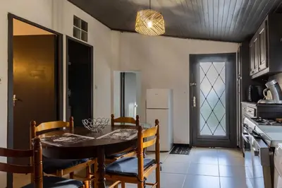 a dining room with a table and chairs and a kitchen at Casa Calma - Maison à proximité des plages in Figari