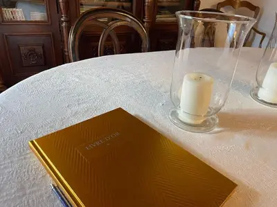 a book on a table with a candle and a vase at Appartement familial au cœur du village d’Olmeto in Olmeto
