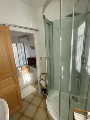 a bathroom with a glass shower and a bedroom at Appartement familial au cœur du village d’Olmeto in Olmeto