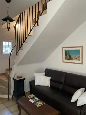 a living room with a black couch and stairs at Appartement familial au cœur du village d’Olmeto in Olmeto
