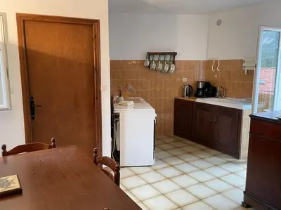 a kitchen with a table and a white refrigerator at Appartement familial au cœur du village d’Olmeto in Olmeto