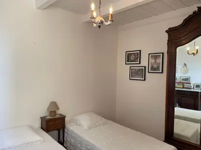 a bedroom with two beds and a mirror and a chandelier at Appartement familial au cœur du village d’Olmeto in Olmeto