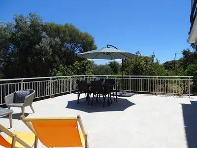 a patio with a table and chairs and an umbrella at Charmant rez de villa, et sa terrasse à Ajaccio in Ajaccio
