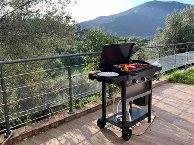 a barbecue grill on a deck with a view of a mountain at Magnifique bergerie corse du 17eme Siècle à proximité des plages in Eccica-Suarella