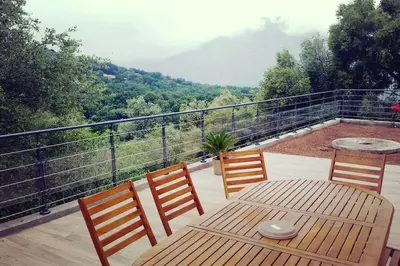 a wooden table and chairs on a balcony with a view at Magnifique bergerie corse du 17eme Siècle à proximité des plages in Eccica-Suarella