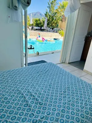 a bedroom with a bed with a view of a pool at maison de rêve dans un écrin de verdure au calme in Eccica-Suarella