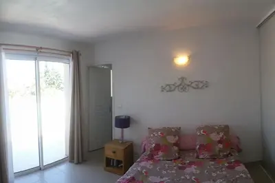 a bedroom with a bed and a sliding glass door at maison de rêve dans un écrin de verdure au calme in Eccica-Suarella
