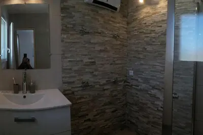 a bathroom with a sink and a stone wall at maison de rêve dans un écrin de verdure au calme in Eccica-Suarella
