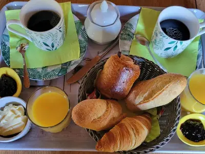a table with a basket of croissants and cups of coffee at A VIGNA VECCHIA chambre d'hôtes in Porto-Vecchio