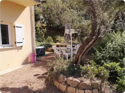 a patio with a table and chairs under a tree at Appartement moderne et calme à Sartène en Corse du Sud in Sartène