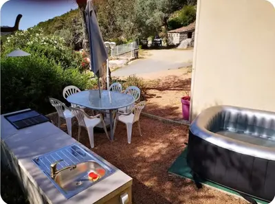 a grill and a table with chairs and a sink at Appartement moderne et calme à Sartène en Corse du Sud in Sartène