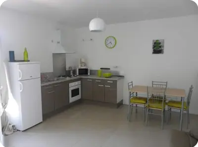 a kitchen with a table and a white refrigerator at Appartement moderne et calme à Sartène en Corse du Sud in Sartène