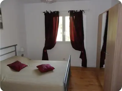 a bedroom with a bed with red pillows and a window at Appartement moderne et calme à Sartène en Corse du Sud in Sartène