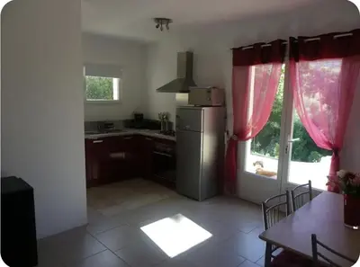 a kitchen with a refrigerator and a table and a window at Gîte au coeur d'une oliveraie in Sartène