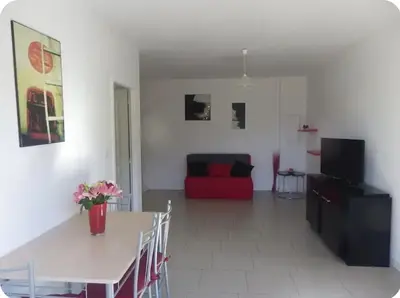 a living room with a table and a red couch at Gîte au coeur d'une oliveraie in Sartène
