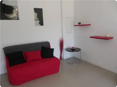 a red couch in a room with a table at Gîte au coeur d'une oliveraie in Sartène