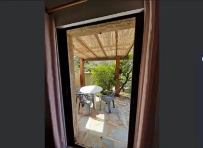 a window view of a patio with a table and chairs at Petit nid douillet à deux pas de Santa Giulia in Porto-Vecchio
