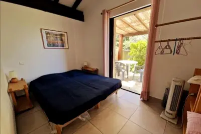 a bedroom with a bed and a sliding glass door at Petit nid douillet à deux pas de Santa Giulia in Porto-Vecchio