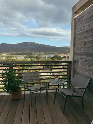 a patio with two chairs and a table on a deck at Appartement fonctionnel 4p avec piscine et vue mer in Porto-Vecchio