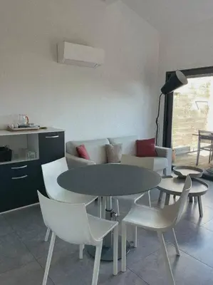 a living room with a table and chairs and a couch at Appartement fonctionnel 4p avec piscine et vue mer in Porto-Vecchio