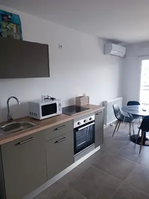 a kitchen with a microwave and a sink and a table at Très beau T2 in Ajaccio