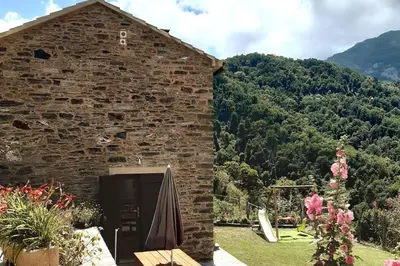 a brick building with an umbrella next to a mountain at Maison de charme Orezza Haute-Corse Castagniccia in Carpineto