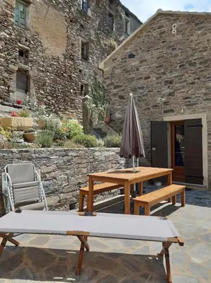 a patio with two tables and an umbrella at Maison de charme Orezza Haute-Corse Castagniccia in Carpineto