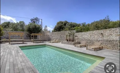 a swimming pool in front of a stone wall at CASA BIANCA 6 personnes Piscine Chauffée in Bonifacio