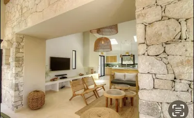 a living room with a stone wall at CASA BIANCA 6 personnes Piscine Chauffée in Bonifacio