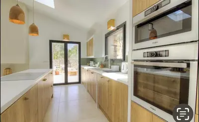 a kitchen with wooden cabinets and white counter tops at CASA BIANCA 6 personnes Piscine Chauffée in Bonifacio
