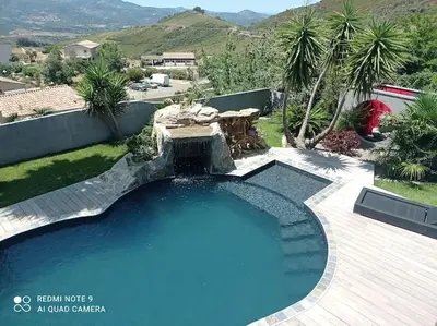 a large swimming pool with a fountain in a yard at Appartement F2 dessous de villa in Olmeta-di-Tuda