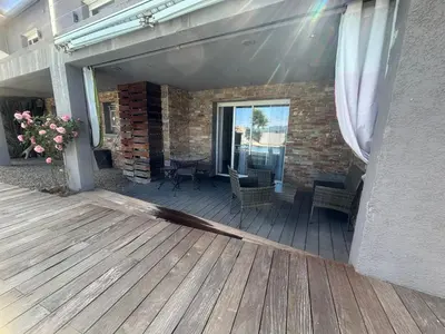 a deck with chairs and tables on a building at Appartement F2 dessous de villa in Olmeta-di-Tuda