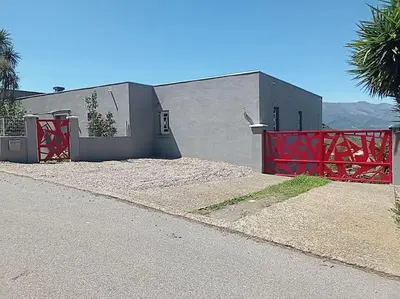 a house with a red gate next to a building at Appartement F2 dessous de villa in Olmeta-di-Tuda