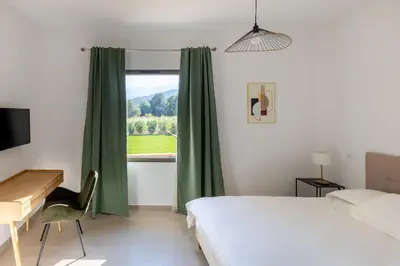 a bedroom with a bed and a desk and a window at Villa avec piscine in Ghisonaccia