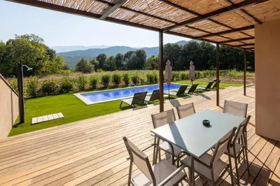 a patio with a table and chairs and a swimming pool at Villa avec piscine in Ghisonaccia