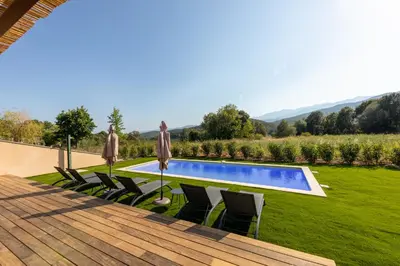 a pool with chairs and umbrellas in a yard at Villa avec piscine in Ghisonaccia