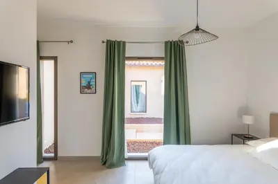a bedroom with a bed and a window with green curtains at Villa avec piscine in Ghisonaccia