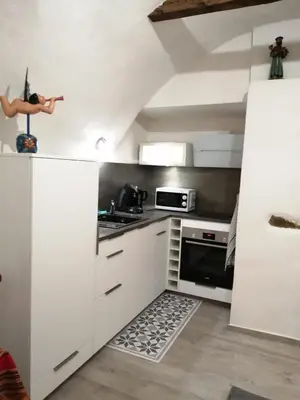 a kitchen with white cabinets and a stove top oven at Studio neuf à 15mn de la mer in Occhiatana