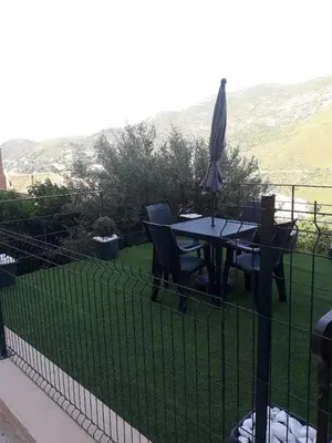a fence with an umbrella and a table and chairs at Studio neuf à 15mn de la mer in Occhiatana
