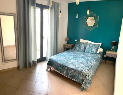 a bedroom with a bed and a blue wall at Bel Appartement en plein cœur de Folelli in Penta-di-Casinca