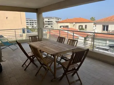 a wooden table and chairs on a balcony at Bel Appartement en plein cœur de Folelli in Penta-di-Casinca