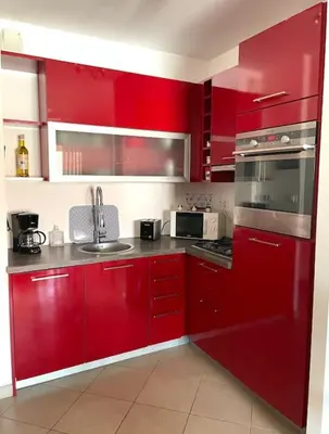 a red kitchen with stainless steel appliances and red cabinets at Bel Appartement en plein cœur de Folelli in Penta-di-Casinca