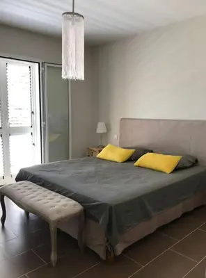 a bedroom with a large bed with yellow pillows at Maison à Saint-Florent avec piscine privée in Oletta