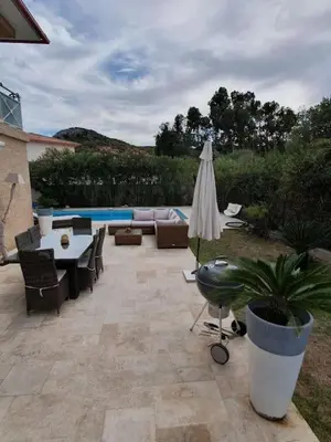 a patio with a table and an umbrella and a pool at Maison à Saint-Florent avec piscine privée in Oletta