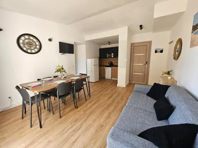 a living room with a table and a blue couch at Très bel appartement T3 dans résidence hotellière 