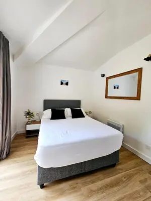a bedroom with a large white bed and a mirror at Très bel appartement T3 dans résidence hotellière 